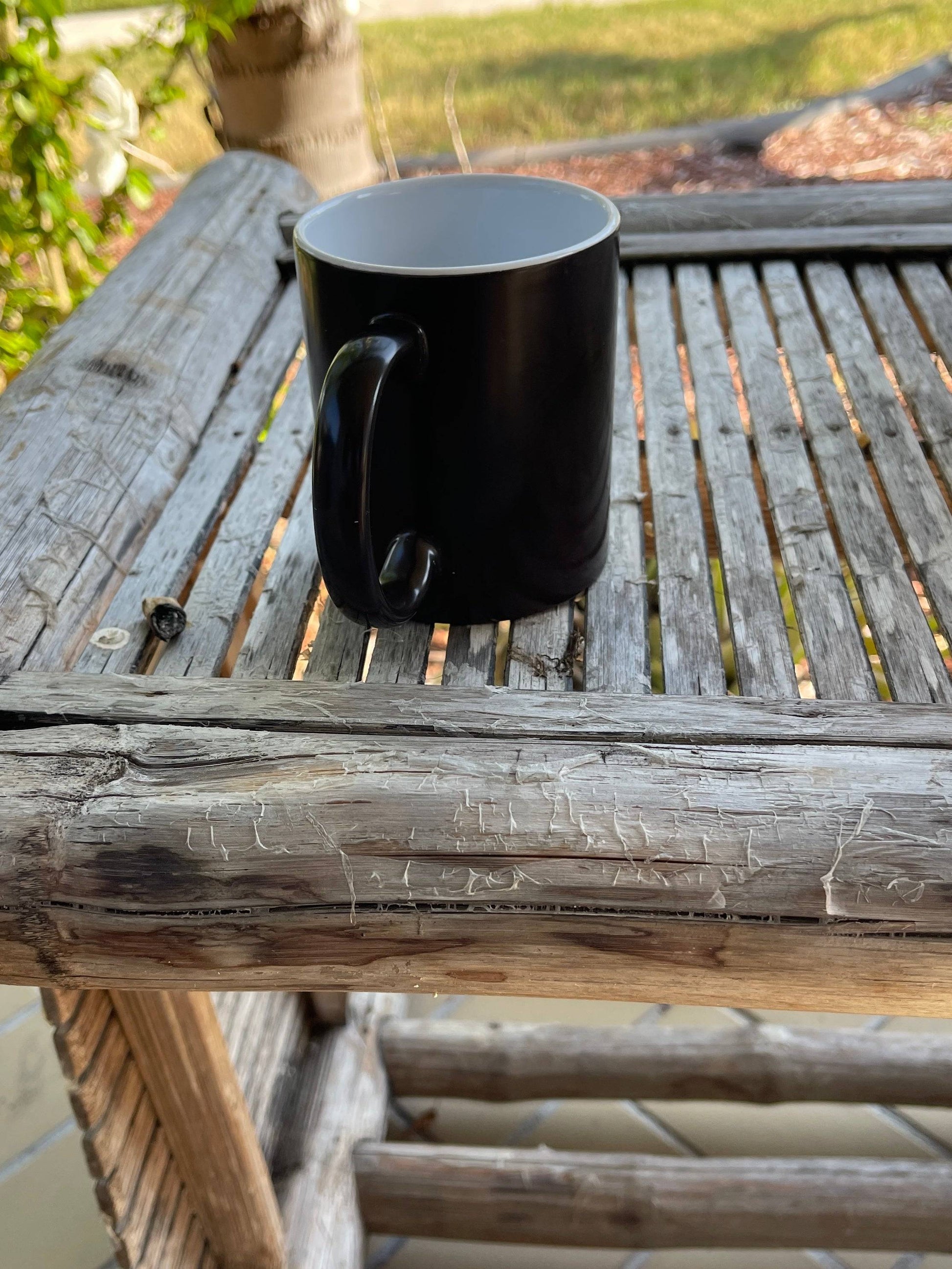 a black coffee cup sitting on top of a wooden table