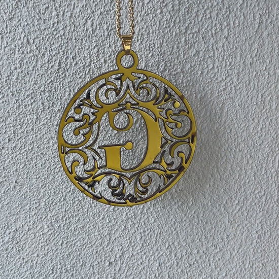 a gold necklace with the letter g medallion attach to it