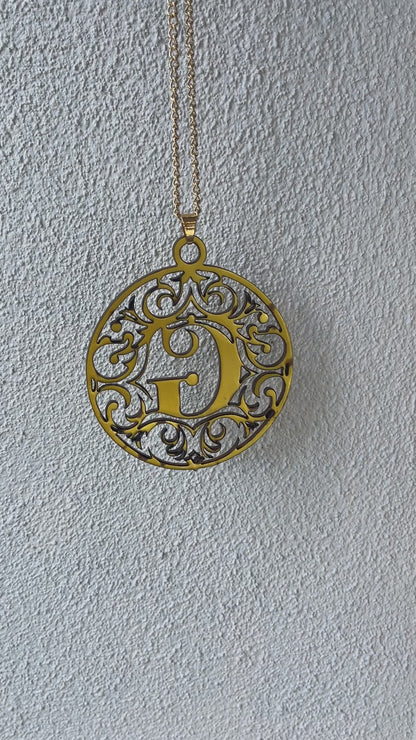 a gold necklace with the letter g medallion attach to it