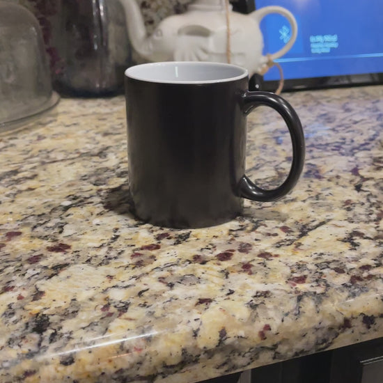 a black coffee mug sitting on top of a counter